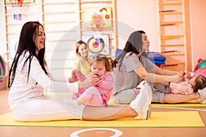 Babies have fun while mothers doing workout in gym class to loose extra weight. Child-friendly fitness for women with