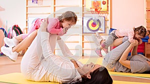 Babies have a fun while mothers doing workout in gym class to loose extra weight. Child-friendly fitness for women with