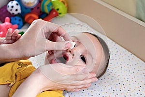 babies and newborn hygiene and healthcare. Closeup of cleaning and washing baby face with soft cottong pad