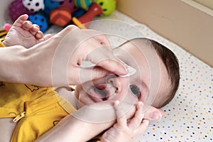 babies and newborn hygiene and healthcare. Closeup of cleaning and washing baby face with soft cottong pad