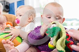 Babies with pacifier in toddler group playing with toys