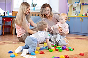 Babies play and their mothers communicate in playroom