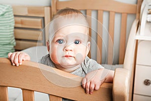 Baby 8 months on crib. Children`s facial expressions, newborn care concept, healthy sleep, colic, teething