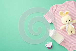 Baby accessories concept. Top view photo of infant clothes pink bodysuit knitted bunny toy milk bottle and pacifier on isolated