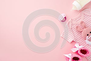 Baby accessories concept. Top view photo of pink infant clothes bodysuit booties baby`s dummy bottle and knitted bunny rattle toy