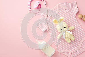 Baby accessories concept. Top view photo of pink infant clothes bodysuit bottle wooden rattle pacifier chain and knitted bunny toy