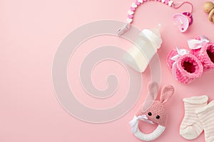 Baby accessories concept. Top view photo of tiny pink shoes socks knitted bunny rattle toy pacifier chain wooden rattle and bottle