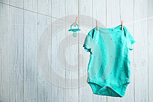 Baby accessories on laundry line against wooden background.