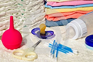 Baby accessories: pacifier, bottle of milk, disposable diapers, scissors, clothes, enema, cotton swab