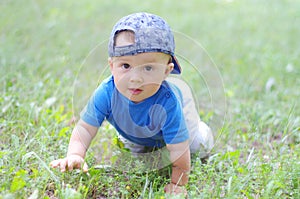 Baby age of 10 months creeps on grass in summer