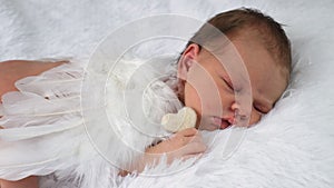 Baby with angel wings sleeps on the bed. Selective focus.