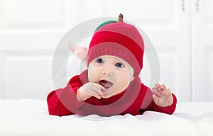 Baby in apple hat. Kid on bed. Child at home