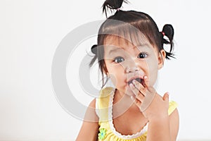 Baby asian child girl eating noodle by herself and making a mess on her face and hand