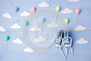 Baby background with balloons, white clouds and baby boy shoes on blue wooden background