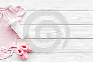 Baby background - pink color. Clothes, booties and accessories for newborn girl on white wooden table top-down frame
