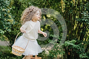 Baby with basket full of colorful eggs. Easter egg hunt.