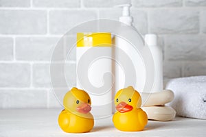 Baby bath accessories, towel, yellow rubber duck and shampoo bottles. The concept of child care