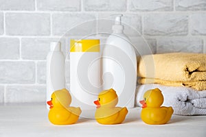 Baby bath accessories, towel, yellow rubber duck and shampoo bottles. The concept of child care