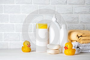 Baby bath accessories, towel, yellow rubber duck and shampoo bottles. The concept of child care