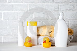 Baby bath accessories, towel, yellow rubber duck and shampoo bottles. The concept of child care