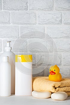 Baby bath accessories, towel, yellow rubber duck and shampoo bottles. The concept of child care