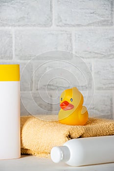 Baby bath accessories, towel, yellow rubber duck and shampoo bottles. The concept of child care
