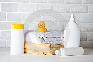 Baby bath accessories, towel, yellow rubber duck and shampoo bottles. The concept of child care