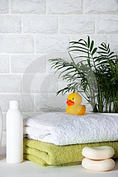 Baby bath accessories, towel, yellow rubber duck and shampoo bottles. The concept of child care