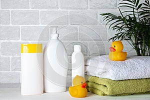 Baby bath accessories, towel, yellow rubber duck and shampoo bottles. The concept of child care