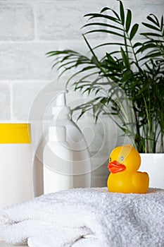 Baby bath accessories, towel, yellow rubber duck and shampoo bottles. The concept of child care