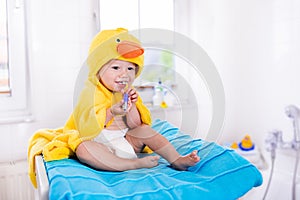 Baby in bath towel with tooth brush