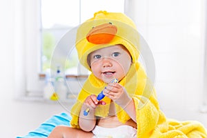 Baby in bath towel with tooth brush