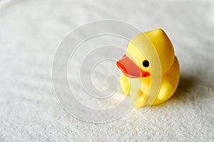 Baby bath toy yellow duck on white towel, copy space. child care