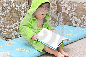 Baby in bathrobe reading book