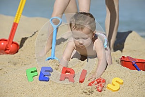 Baby on the beach with writing ferias