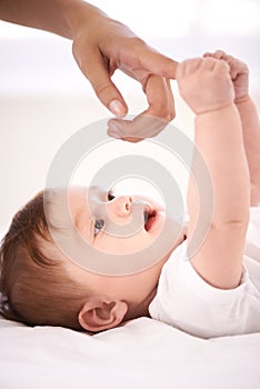 Baby, bed and mom for holding finger with care, bonding and love with connection in family home. Infant, newborn and