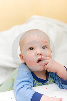 Baby on bed put fingers in mouth