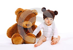 Baby with big teddy bear toy on white