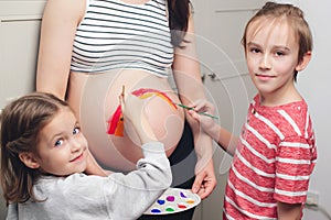 Baby birth expecting time and belly painting. Happy children and pregnant mom having fun together at home