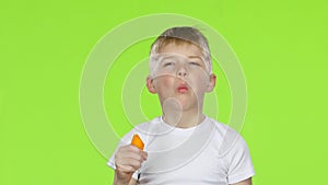 Baby bites a carrot and shows a thumbs up. Green Screen