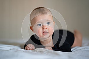 Baby in black clothes lying on paunch on white bed