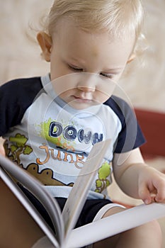 Baby blond boy with book indoors