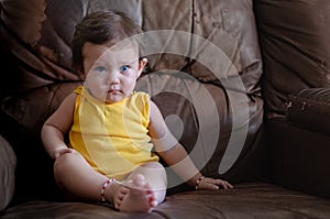 Baby blue eyes girl seated on an old couch
