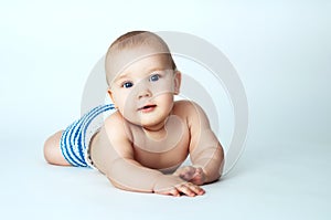 Baby with blue eyes lying on a gray background