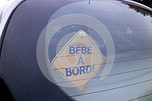 Baby on board sign in French at the back of a car