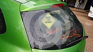 Baby on board yelllow sign on green car photo