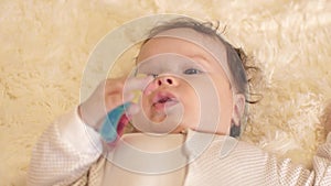 Baby in body lies on his back in crib and holds toy in his hands.