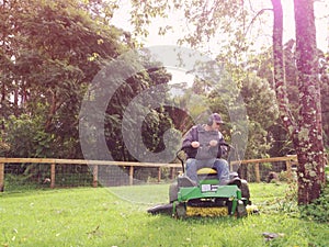 Baby boomer mowing grass on ride on mower photo