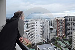 Baby boomer retired man looks at view of apartment buildings in photo