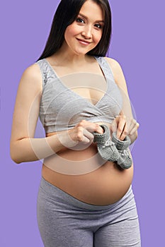 Baby booties for unborn child on the belly of pregnant woman